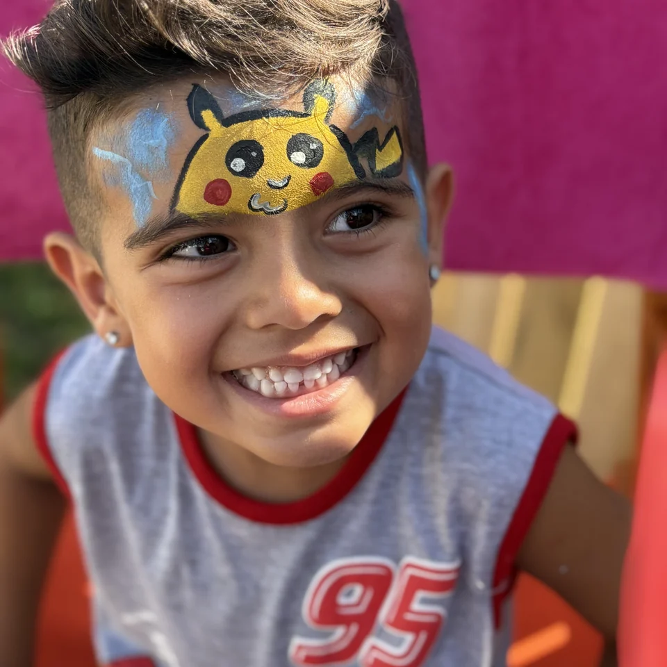 Close-up of a smiling child with Pikachu face paint.