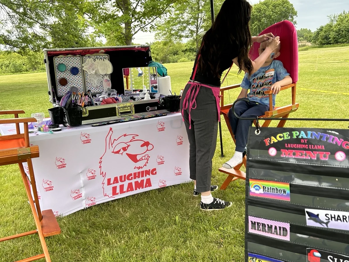 Mel painting a guest at an outdoor face painting station.