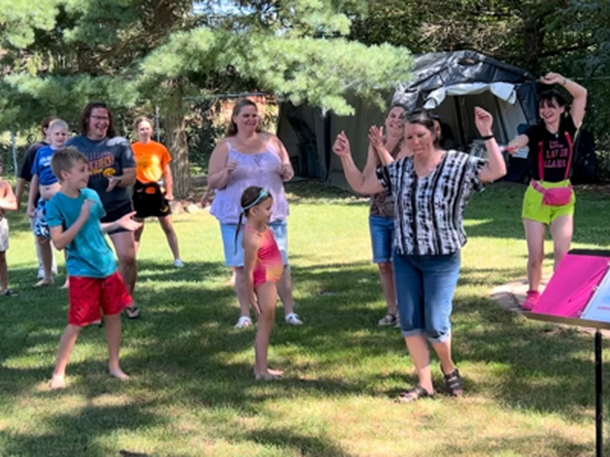 Mel leading a laughter yoga activity with a group outdoors.
