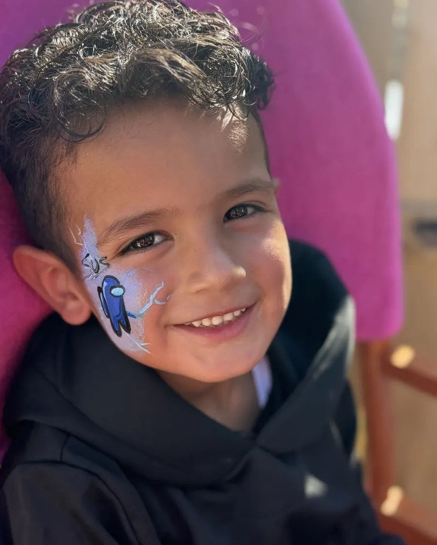 Child smiling with custom blue character face paint by Laughing Llama.