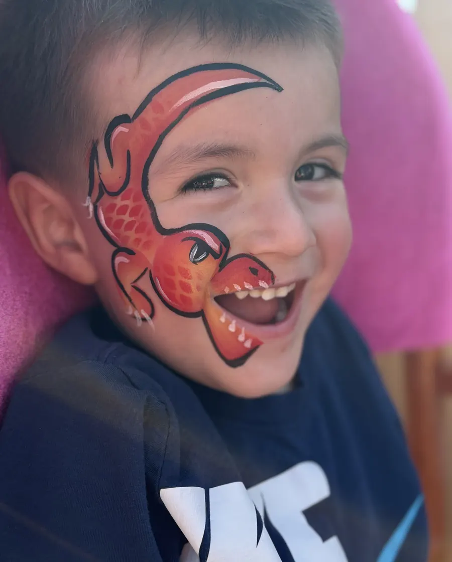 Child laughing with bright dinosaur face painting by Laughing Llama at a Wisconsin event.