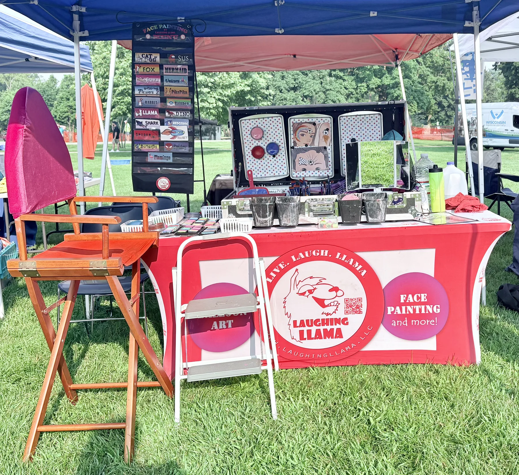 Professional Laughing Llama face painting setup for festivals and community events.