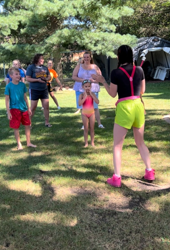 Mel leading a playful laughter yoga group activity outdoors in Wisconsin.